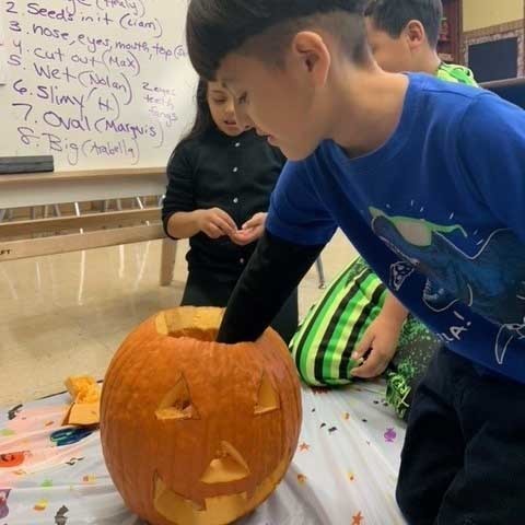 student carving pumpkin